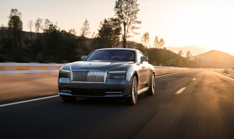 The new Rolls-Royce, Spectre, on the road in the sunset.