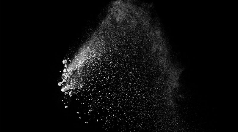 Digital image of metal powder being blown in the air on a black background to support Sandvik article