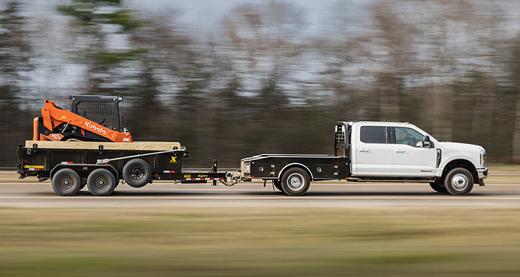 small digger on a trailer being towed by a pickup truck