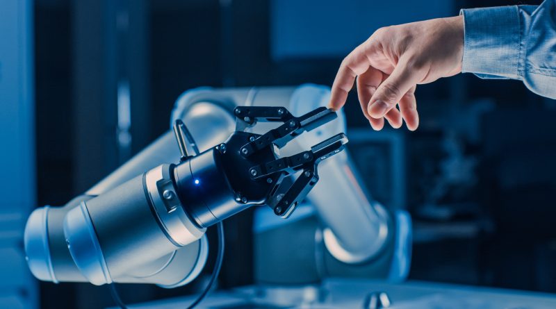 Image of a robotic hand reaching out to touch a human hand in a warehouse to support Atlas article