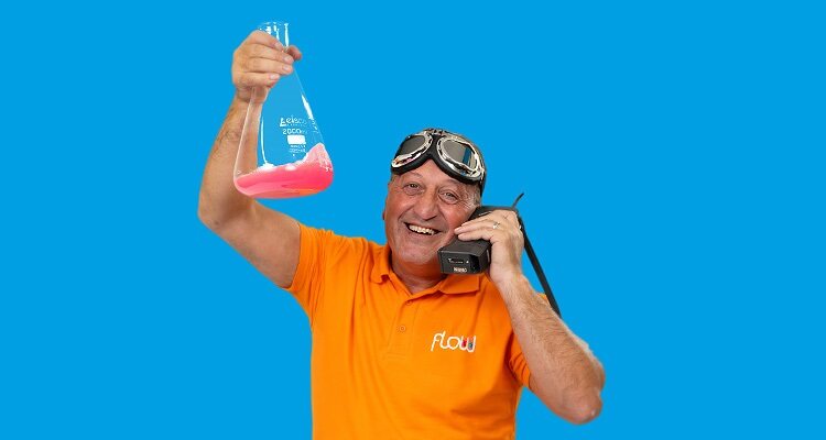 Man in orange T-Shirt holding conical flask with red liquid inside
