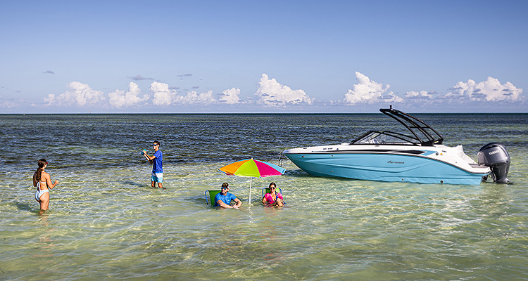 kids playing while their parents relax in the ocean near their hurricane deck boat