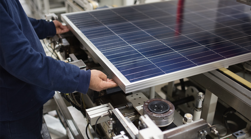 Manufacturing worker in a warehouse working on a solar panel to support solar panel manufacturing article