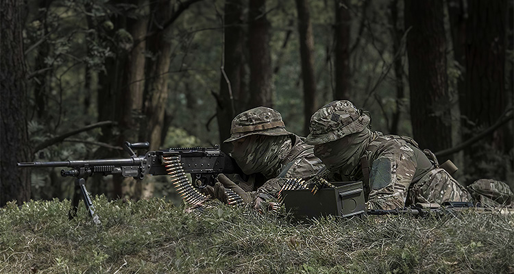 twosoldiers in camouflage with belt fed machine gun