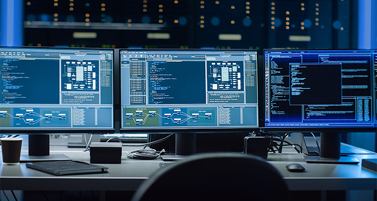 Three computer monitors showing various data screens