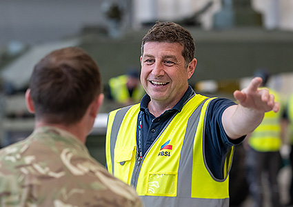 RBSL worker in hi visibility jacket talking to military officer