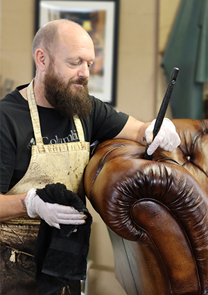 craftsman working on brown leather sofa