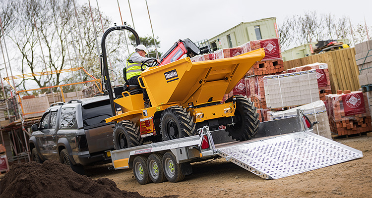 Flatbed trailer carrying yellow dump truck