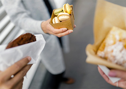 People holding pastries in paper & board packaging