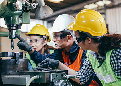 Asian male foreman manager showing case study of factory machine to two engineer trainee young woman in protective uniform. teamwork people training and working in industrial manufacturing business