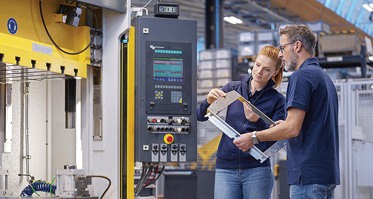 Coworkers discussing over equipment in metal industry