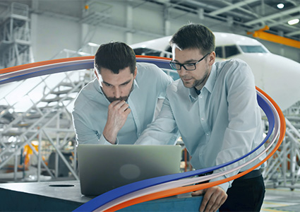 2 technicians study a laptop in front of an aircraft