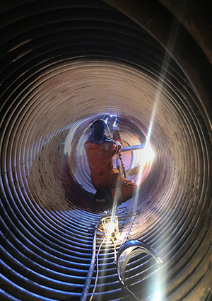 Man welding inside metal pipe