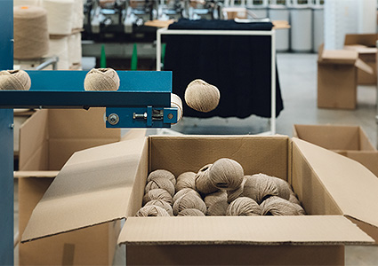 Balls of wool falling from conveyor into cardboard box