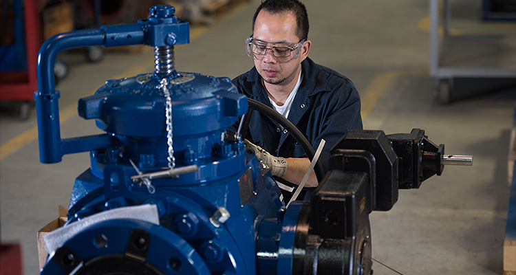 a man working on a blue industrial pump or valve