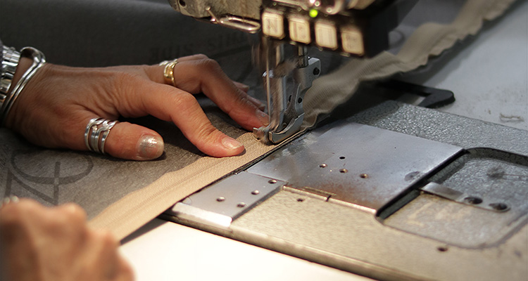 a close-up of hands using a sewing machine to stitch a zipper onto a piece of fabric
