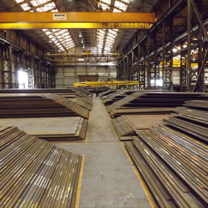 a large warehouse storing stacks of abrasion-resistant (AR) steel plates.