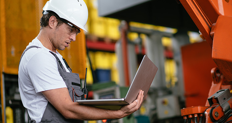 an engineer or technician in a manufacturing or industrial setting using a laptop