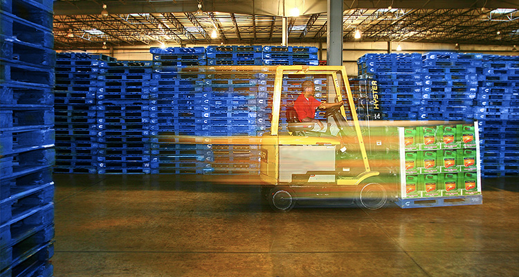 How Product as a Service (PaaS) supports long-term growth in manufacturing a forklift operating in a warehouse filled with stacks of blue pallets