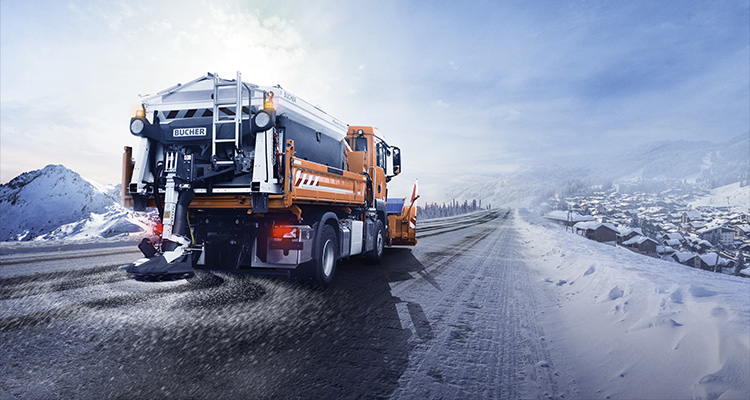 Through cutting-edge technology, Bucher Municipal transforms municipal cleaning with sustainable, future-ready solutions a Bucher Municipal snowplow and salt spreader truck clearing a snowy road