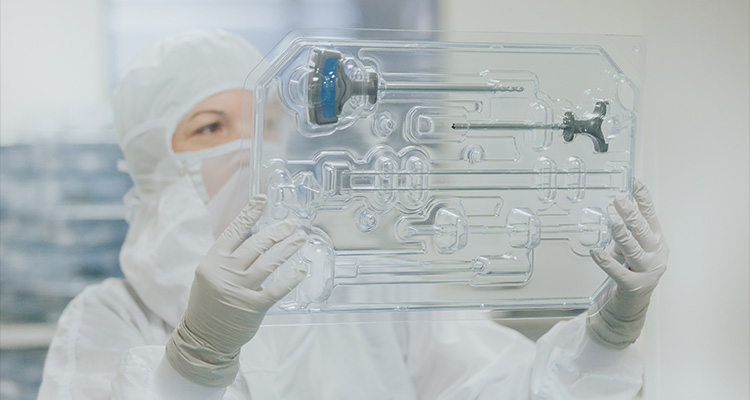 a person in a cleanroom handling a sterile-packaged medical device kit
