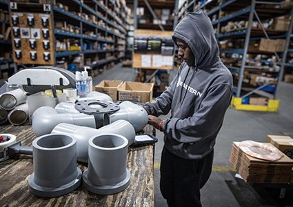 a person working with PVC pipe fittings in a warehouse