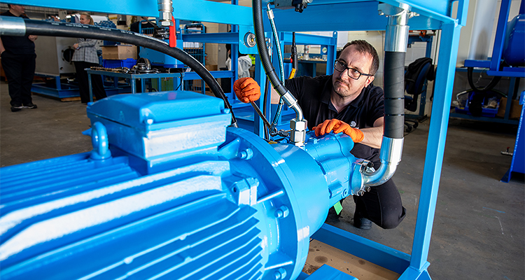 a man working on a large, blue hydraulic pump or system