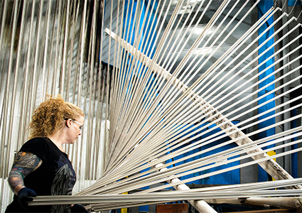 a worker handling aluminum profiles in a vertical powder coating or anodizing production line. 