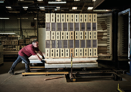 a worker loading a kiln car with ceramic products