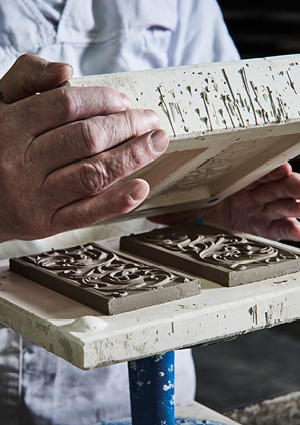 a craftsperson using traditional techniques to create handmade tiles.