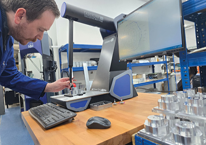 an industrial coordinate measuring machine (CMM) being operated in a manufacturing setting to inspect metal parts