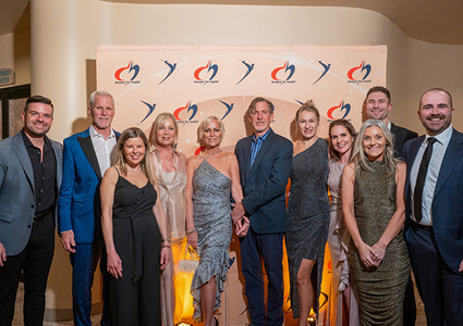a group of people at a formal event standing in front of a step and repeat backdrop featuring the logo of Designs for Health
