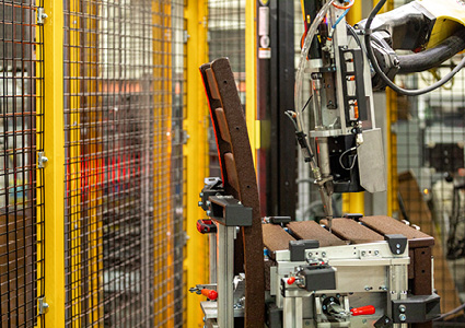 an industrial manufacturing scene featuring a robotic arm and machinery within a safety cage
