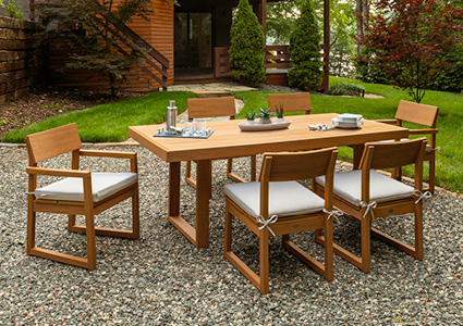an outdoor dining set arranged on a gravel patio in a backyard
