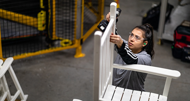 a person in a warehouse setting assembling or constructing white furniture