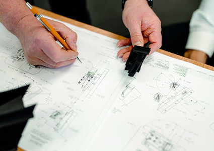  two people working together over a set of technical drawings