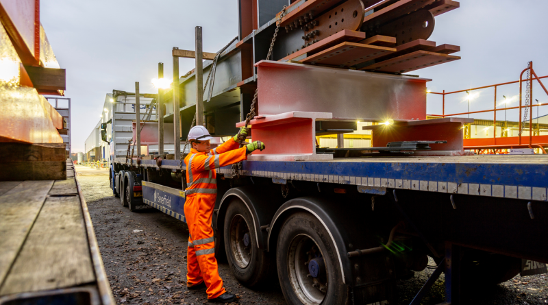 Driver Wearing Full PPE and Chaining Down a Load of Steel Structures