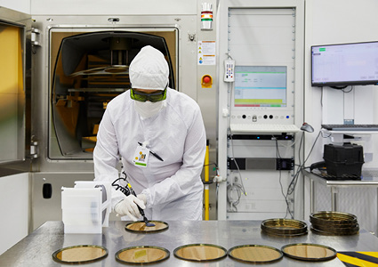 an employee at Coherent inspecting components in a cleanroom environment