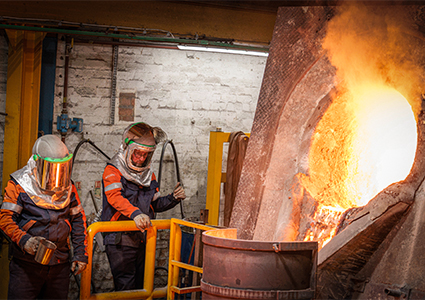 an industrial melting furnace operating inside a metal foundry