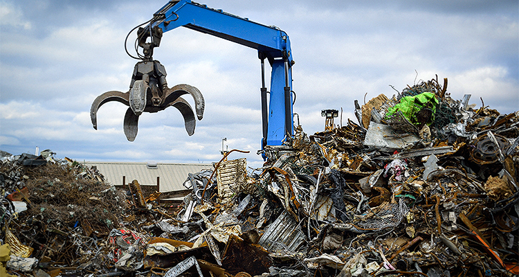 Blue hydraulic Clow Crane used for picking up scrap metal at recycling yard