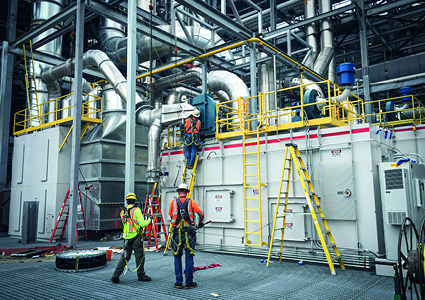 team of industrial technicians performing maintenance or installation work on a large piece of environmental equipment
