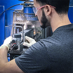 a technician or engineer working closely with precision manufacturing or testing machinery