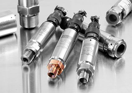a collection of industrial electronic pressure transmitters resting on a reflective metallic surface