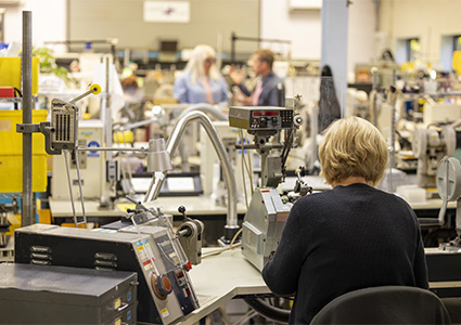  an indoor electronic or mechanical assembly factory floor with workers at their stations