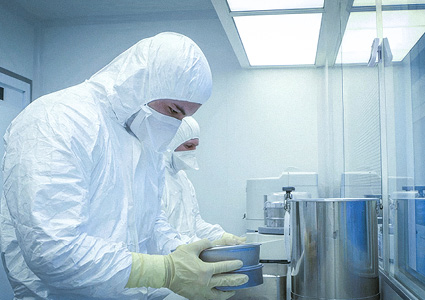 a sterile production environment where personnel are wearing white coveralls and masks for contamination control