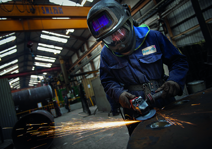 an industrial worker operating an angle grinder to smooth or shape a piece of metal
