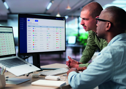 Two men look at a large computer monitor in a modern office