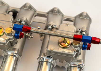 a close-up view of dual automotive carburetors mounted on an intake manifold.