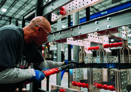 a technician meticulously assembling heavy-duty industrial electrical infrastructure.
