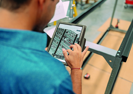 a worker using a digital tablet to review technical references or inventory while on a manufacturing floor